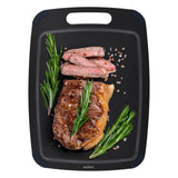 A cooked steak, sliced and garnished with rosemary and coarse salt, is served on a Zyliss Wood Fibre Cutting Board, made from recycled wood fibres. #Large