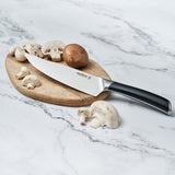 The Zyliss Comfort Pro Chefs Knife 20cm / 8 with an ergonomic handle rests on a wooden cutting board, surrounded by sliced and whole mushrooms on a marble countertop.