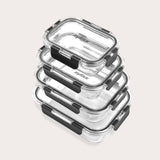 A stack of four clear rectangular glass food containers with black locking lids, arranged neatly on a light background.