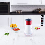 The Zyliss Zick-Zick 2 Food Chopper with a blade cover sits on a kitchen counter next to tortilla chips, salsa, a lime wedge, red chili pepper, and cilantro in a modern kitchen.