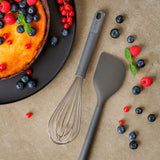 A cheesecake topped with berries sits beside a whisk and a Zyliss Spatula on the countertop, with blueberries, raspberries, and red currants scattered around. #Large