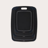 The Zyliss Wood Fibre Cutting Boards set features three nested black boards in different sizes, each with a handle slot and dark gray corner grips, made from eco-friendly recycled wood fibres and shown on a light background. #set of 3