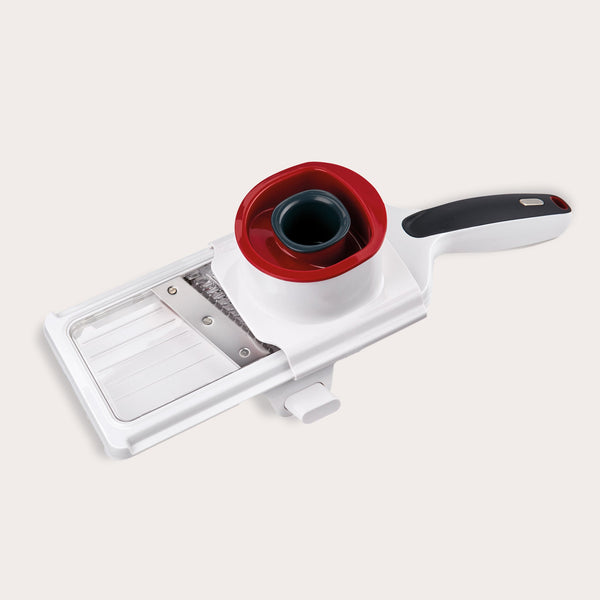The Zyliss Easy Control Handheld Slicer is a white and black tool with a red and black food holder, designed for safe, even vegetable slicing, and features an adjustable thickness selector for custom cuts.