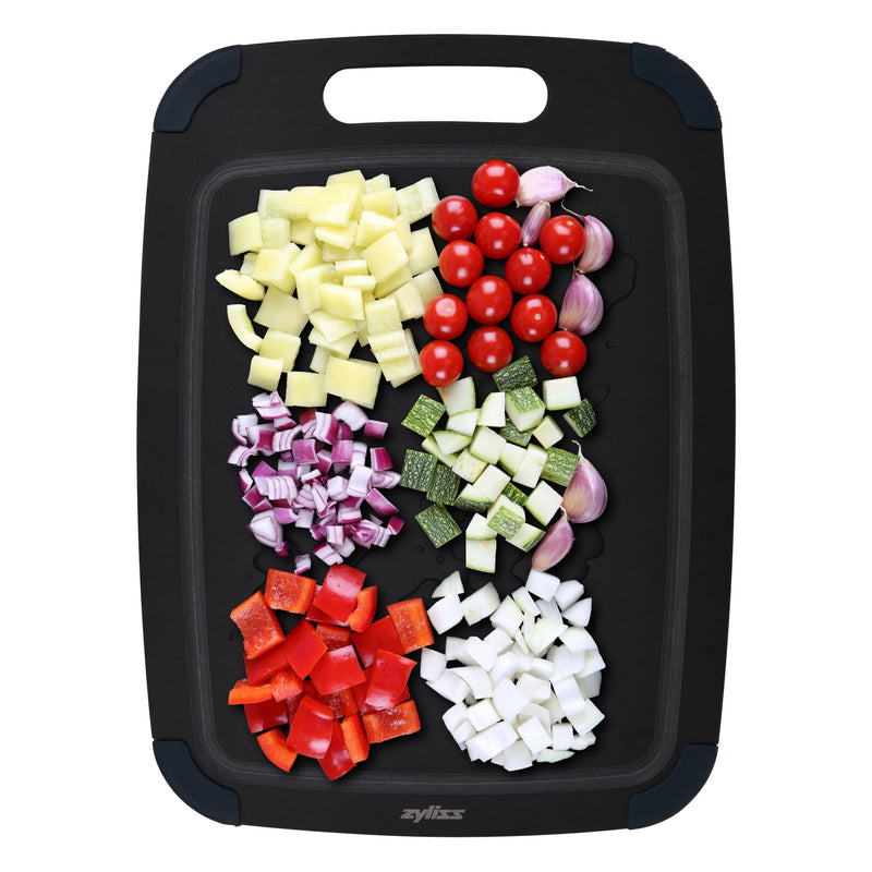 A black Zyliss Wood Fibre Cutting Board holds neatly arranged piles of potatoes, cherry tomatoes, garlic cloves, red onion, zucchini, red bell pepper, and white onion on its eco-friendly recycled wood fibre surface. #Medium