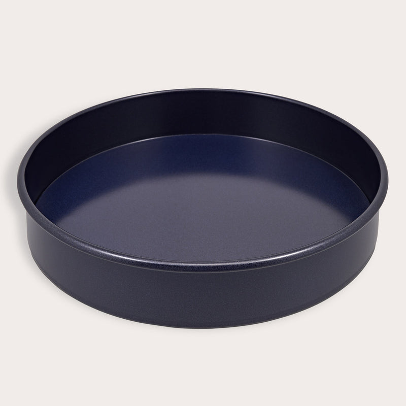 A round, dark Zyliss Durable Non-Stick Removable Base Cake Pan with high sides sits on a light surface, empty. Its smooth nonstick interior ensures easy release and effortless cleanup.