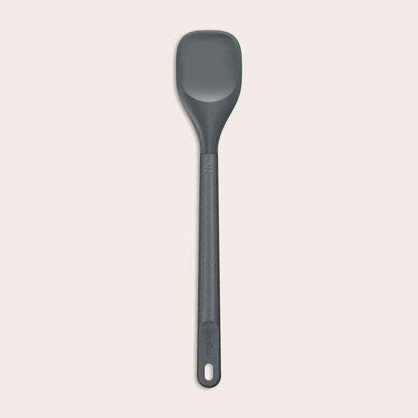 #medium The Zyliss Spoontula is dark gray, with a silicone head, long ergonomic handle, and a gently rounded rectangular bowl, pictured on a plain light background. #Medium