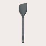 A dark gray Zyliss Spatula with a long handle and a slightly angled, heat-resistant silicone head is displayed on a plain white background. #Large