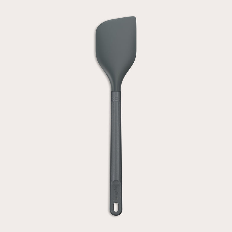 A dark gray Zyliss Spatula with a long handle and a slightly angled, heat-resistant silicone head is displayed on a plain white background. #Large