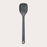 #medium The Zyliss Spoon is a dark gray, heat-resistant silicone utensil with a long handle and end hole, ideal for cooking or serving. Shown against a plain light background. #Medium