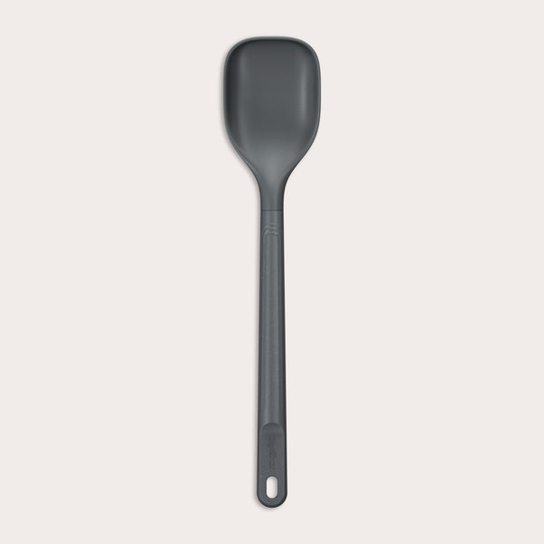#medium The Zyliss Spoon is a dark gray, heat-resistant silicone utensil with a long handle and end hole, ideal for cooking or serving. Shown against a plain light background. #Medium