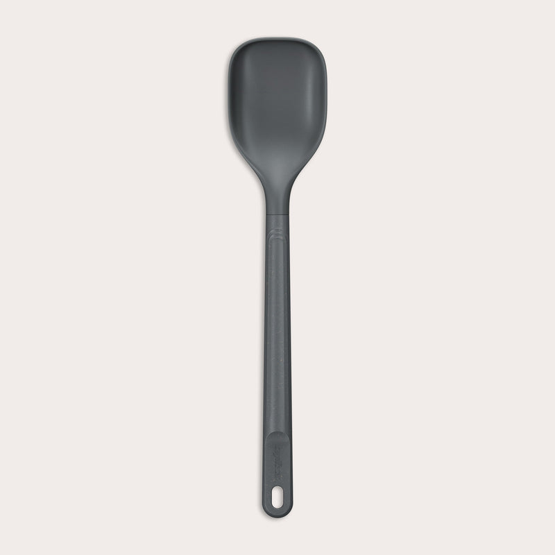 #medium The Zyliss Spoon is a dark gray, heat-resistant silicone utensil with a long handle and end hole, ideal for cooking or serving. Shown against a plain light background. #Medium