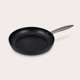 The Zyliss Ultimate Pro Non-Stick Frying Pan With Pouring Lip, crafted from hard-anodized aluminium with a shiny silver handle, features gently sloped sides, a Swiss-engineered coating, and a small pouring spout on one edge. #28cm/11"