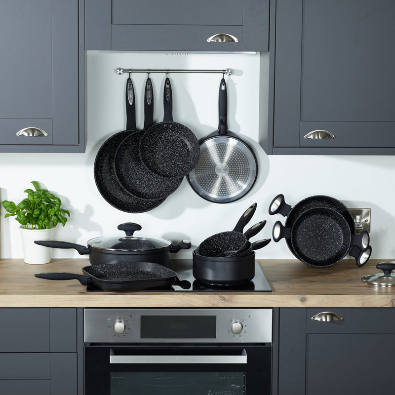 A modern kitchen with grey cabinets, wood countertop, and built-in oven features Zyliss Ultimate Non-Stick Grill Pans with Swiss coating on the stove and countertop, some hanging above. A basil plant decorates the left side. #24cm/9½"
