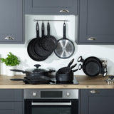 A modern kitchen with gray cabinets and a wooden countertop showcases Zyliss Ultimate Non-Stick Frying Pans, known for their scratch-resistant surface. Some pans hang on a rack; others are on the stove and counter beside a potted basil plant. #28cm/11"
